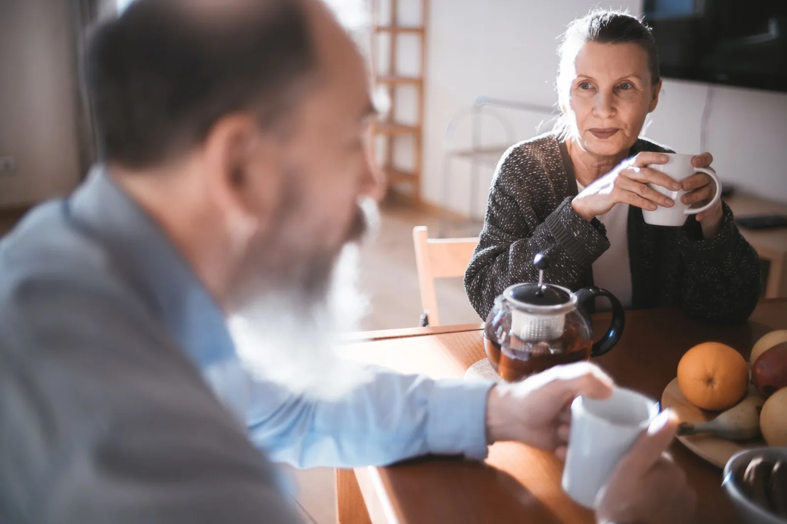 An older couple share coffee together in a cozy kitchen.